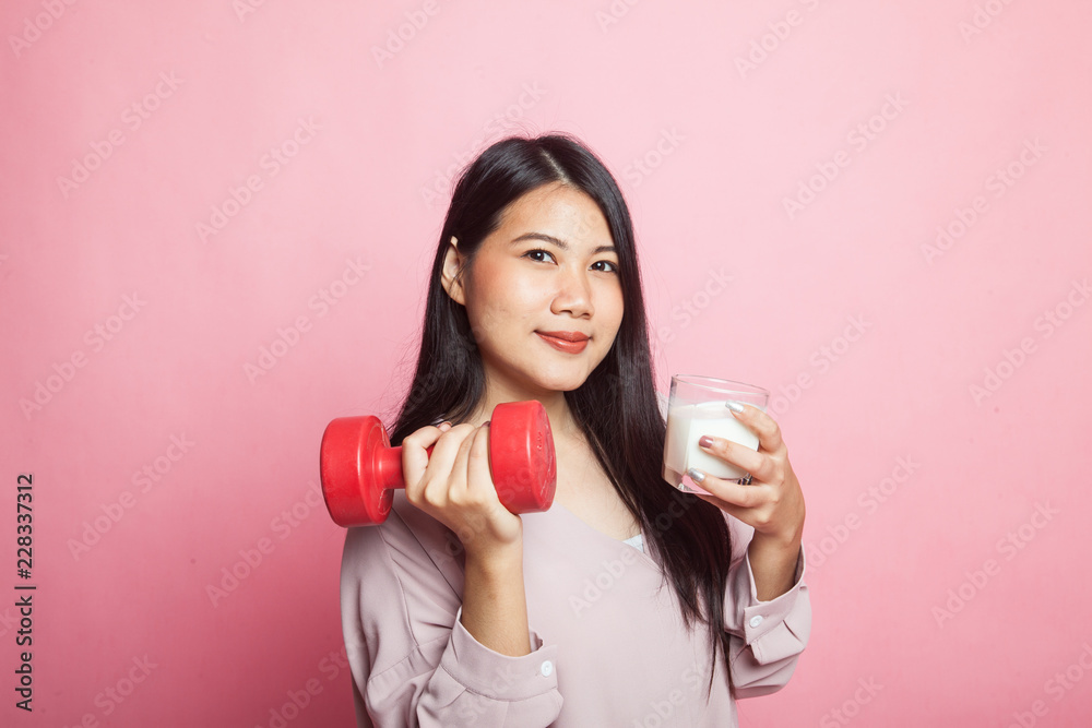 Healthy Asian woman drinking a glass of milk and dumbbell.