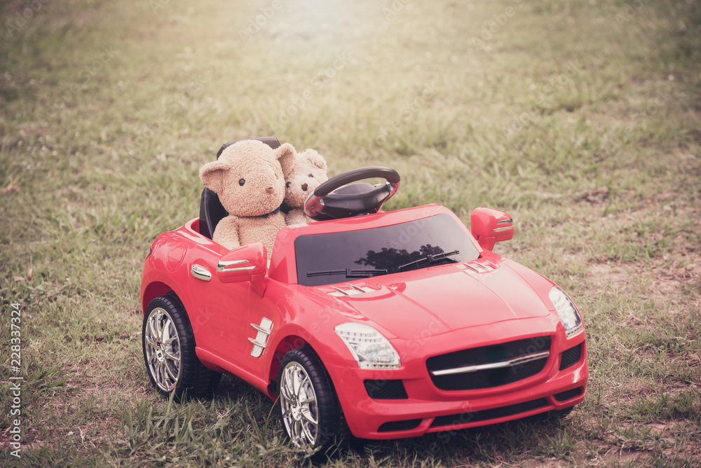 Two teddy bears in big toy car at park Two teddy bears in big toy car at park