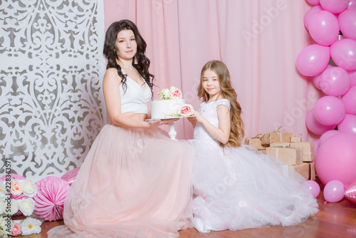 Mom and daughter celebrate their birthday with pink balloons and cake  