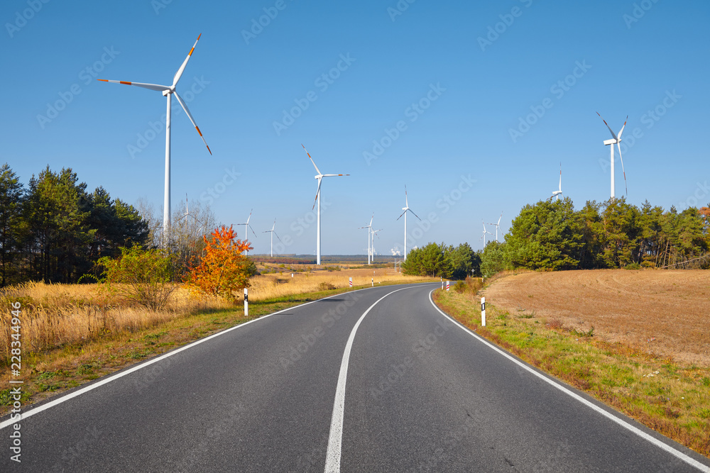 View of a road with windmills in background.