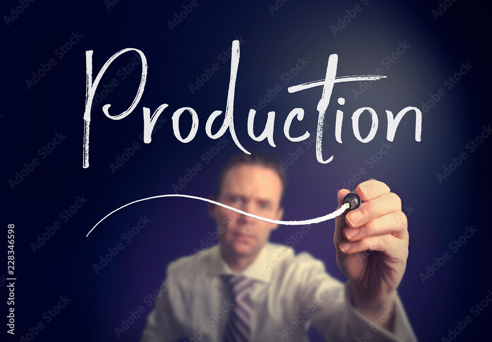 A businessman writing a Production concept with a white pen on a clear screen. A businessman writing a Production concept with a white pen on a clear screen.