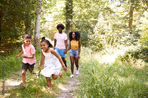 A black couple and their two kids walking in a forest