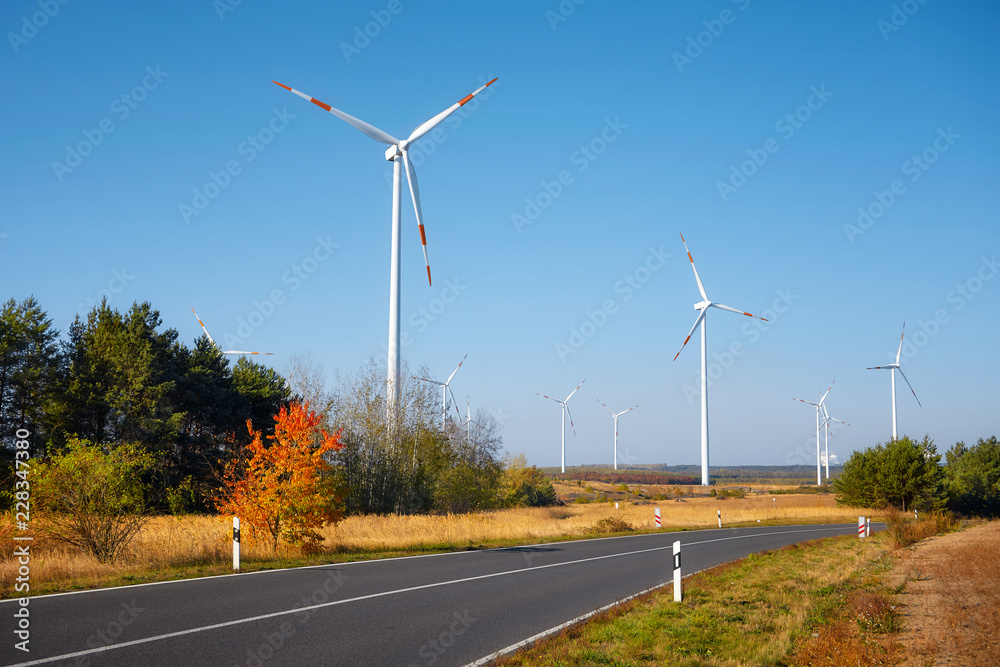 View of a scenic road with windmills in background.