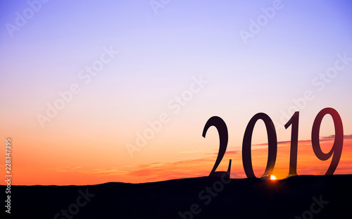2019 in huge numbers, on dark mountains silhouettes, with vivid and beautiful sunrise as background.