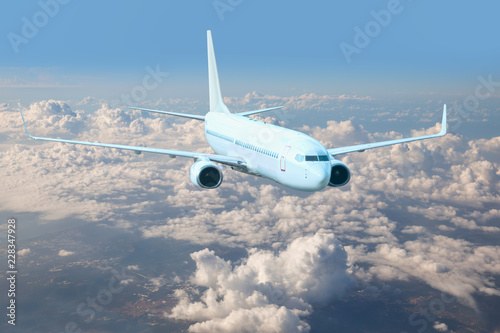 An airplane is flying over low clouds and city with blue sky