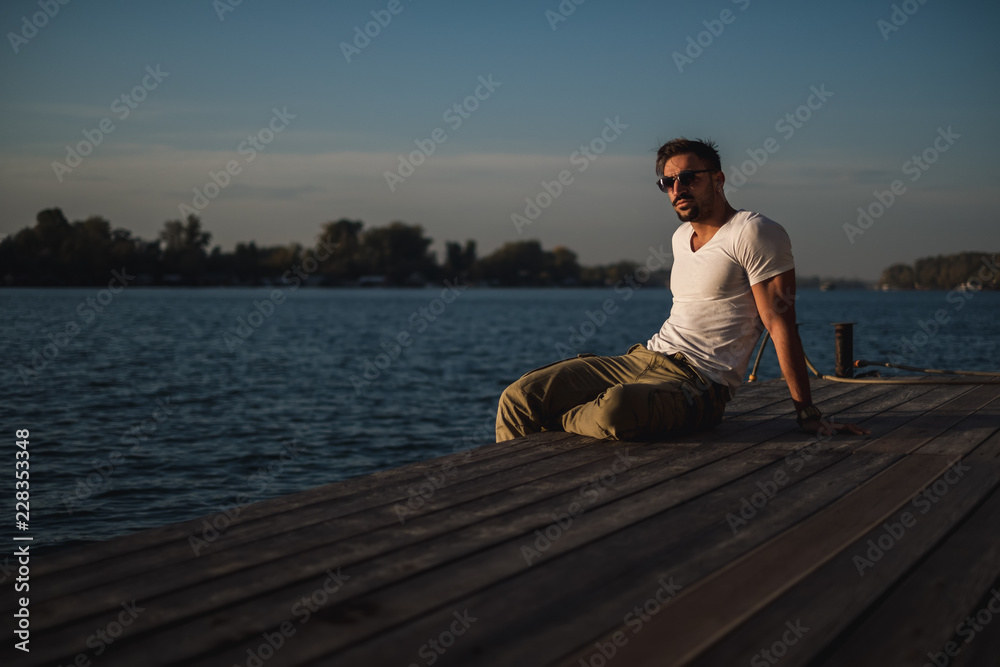 Handsome man relaxing on the river dock