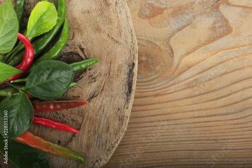 heap of chili pepper with leaves of lemon on wooden background