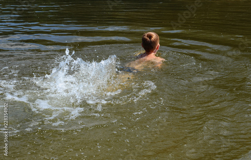 The boy is bathing on the river.