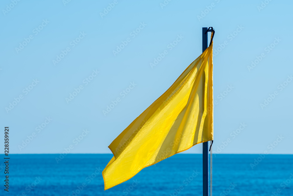 yellow flag against the sea and sky