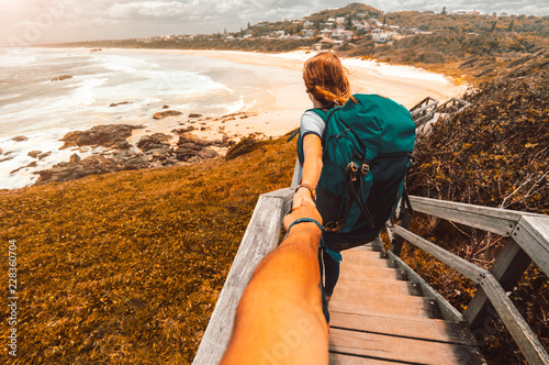 Woman with backpack holding man by hand going to Australia coastline photo