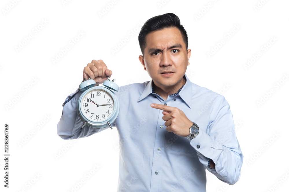 Asian man pointing at an alarm clock with angry expression Asian man pointing at an alarm clock with angry expression