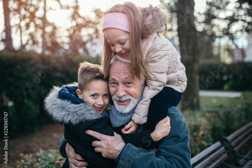 Happy grandfather having fun with his grandchildren in city park. photo