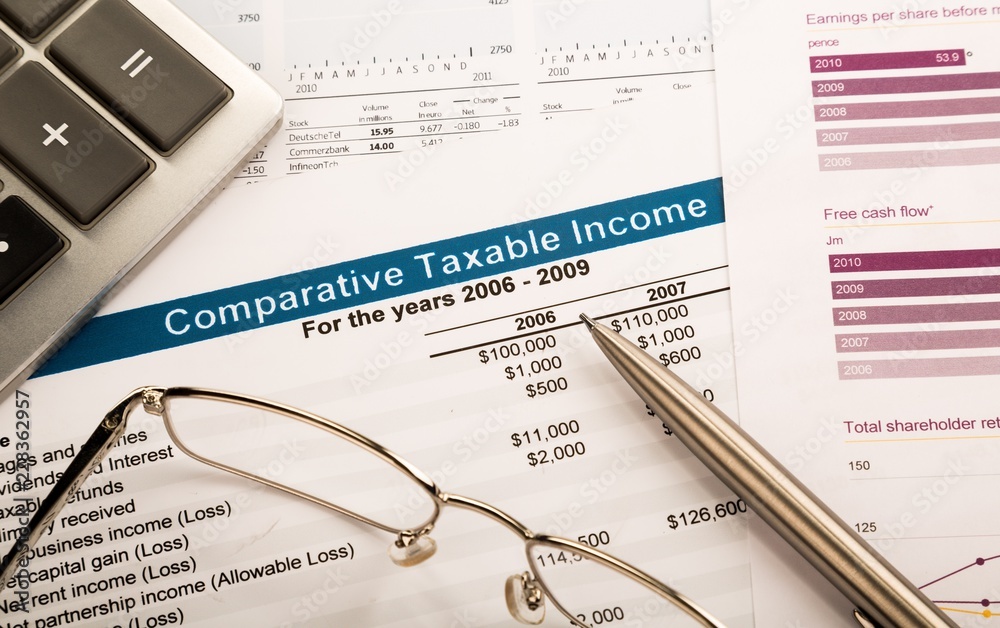 Obraz premium Calculator, Glasses And Pen On Comparative Taxable Income Report