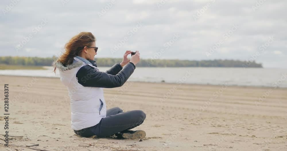 Girl in a warm suit photographs a beautiful sea Girl in a warm suit photographs a beautiful sea