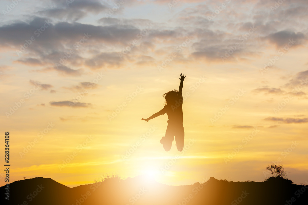 Silhouette of a Happy young woman jumping at the sunset, Freedom and enjoyment concept.