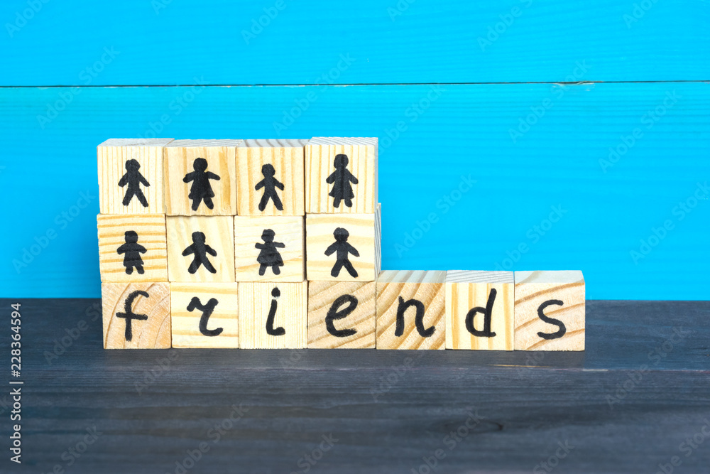 Wooden cubes with word Friends and drawn people on the blue background. Wooden cubes with word Friends and drawn people on the blue background.
