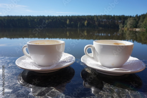 Two cups of morning coffee, standing on the side of the balcony, with a magical view of the lake.