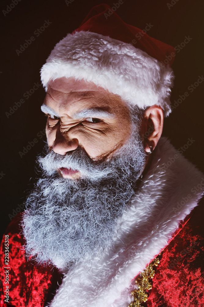 evil Santa Claus grimaces and scares a terrible face on a dark