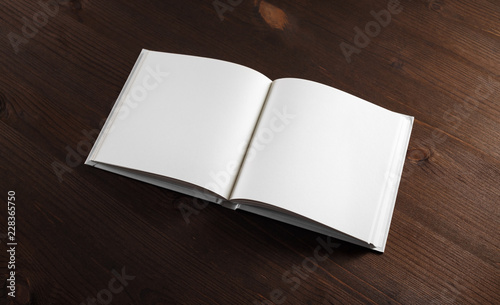 Photo of opened book with blank white pages on wooden background.