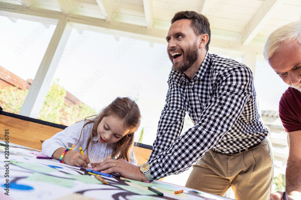 Positive reaction. Serious child bowing head while drawing her family tree Positive reaction. Serious child bowing head while drawing her family tree