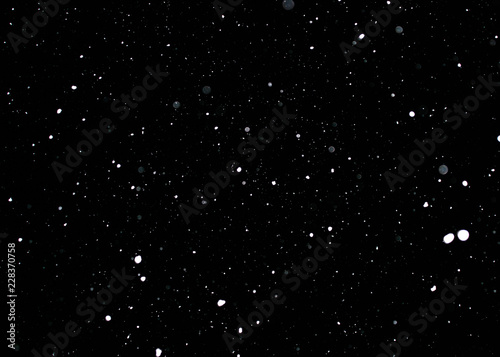 Snowstorm texture. Bokeh lights on black background, shot of flying snowflakes in the air