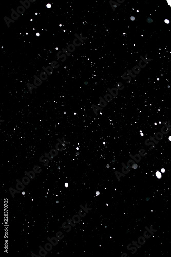 Snowstorm texture. Bokeh lights on black background, shot of flying snowflakes in the air