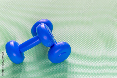 blue weights and dumbbells for sports on light mats © Асель Иржанова