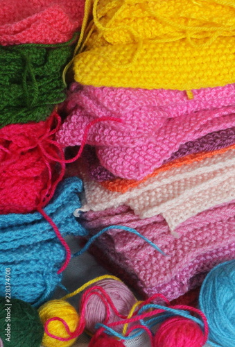 Piles of knitted colorful patches and balls of yarn. 