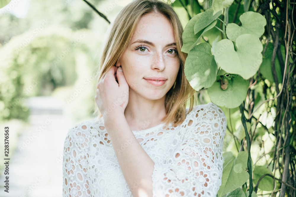 Beautiful attractive young woman posing in spring park wearing white knitted top and blue jeans, modern creative toning Beautiful attractive young woman posing in spring park wearing white knitted top and blue jeans, modern creative toning