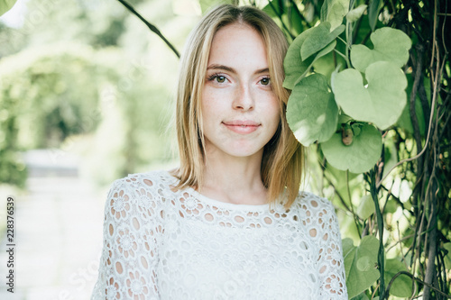Beautiful attractive young woman posing in spring park wearing white knitted top and blue jeans, modern creative toning
