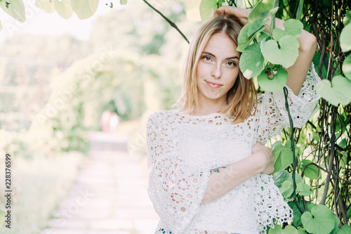 Beautiful attractive young woman posing in spring park wearing white knitted top and blue jeans, modern creative toning photo