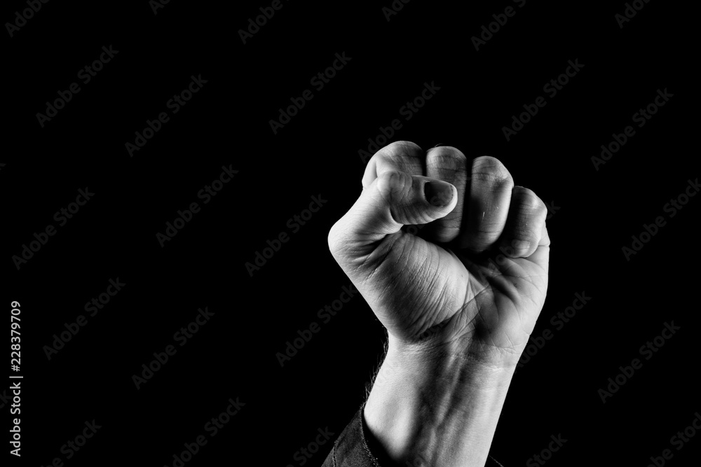 Fist Up. Concept of Power. Man with fist up wearing long sleeve jacket. Black and white, closeup