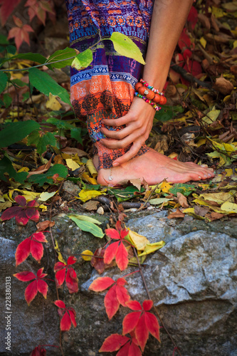 barefoot  woman legs and hands in yoga stretch pose in colorful autumn leaves outdoor