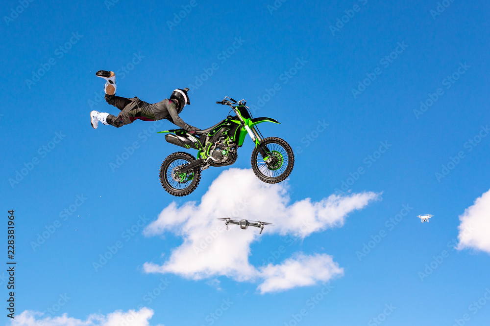 racer on a motorcycle in flight, jumps and takes off on a springboard against the blue sky racer on a motorcycle in flight, jumps and takes off on a springboard against the blue sky