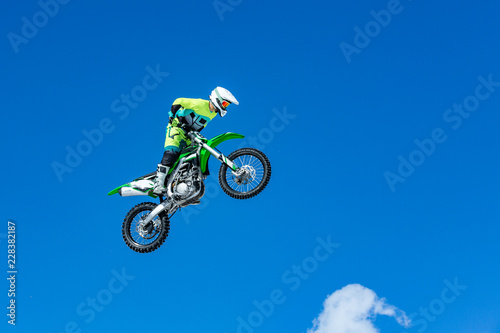 racer on a motorcycle in flight, jumps and takes off on a springboard against the blue sky