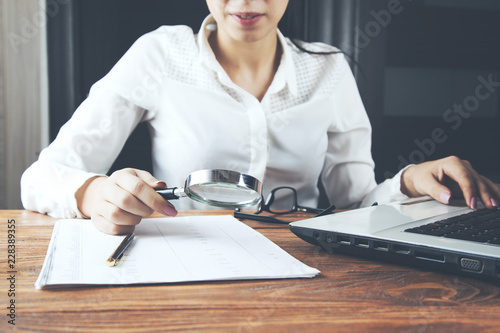 woman hand magnifier and document on desk photo