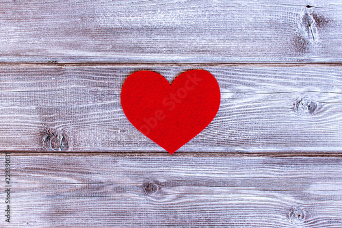 Red felt heart on light vintage wooden background