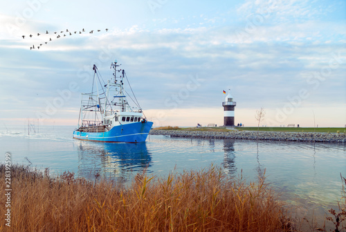 Krabbenkutter kommt zurück in den Heimathafen, Kutterhafen in Wremen mit Leuchtturm an der Wurster Nordseeküste  photo