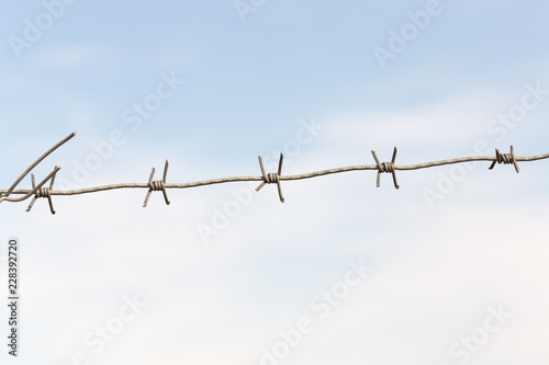 barbed wires against blue sky.