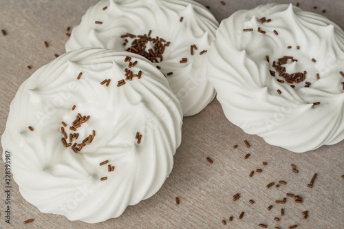 homemade white air meringues and chocolate confectionery decorations on on parchment paper.