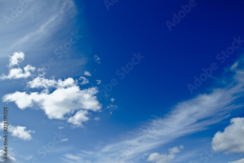 Blue sky with puffy cumulus and thin cirrus clouds.