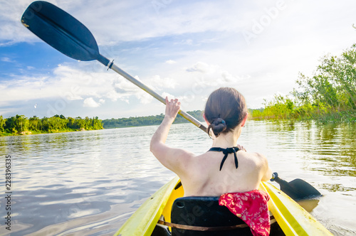 View on girl riding kayak on Amazon river by Leticia in Colombia