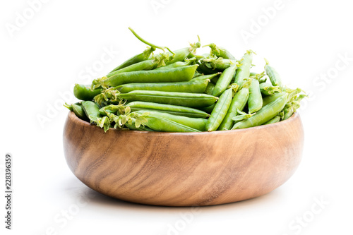 Fresh green pea pods in wooden bowl isolated on white