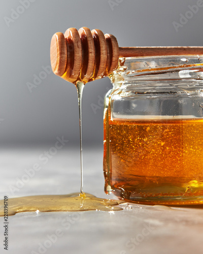 Close-up of natural sweet flower honey dripping from stick on a gray stone table. Rosh hashanah jewish holiday concept.