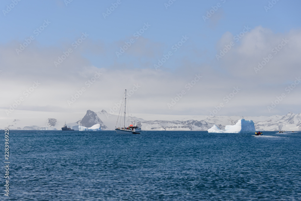 Sailing yacht and iceberg in antarctic sea