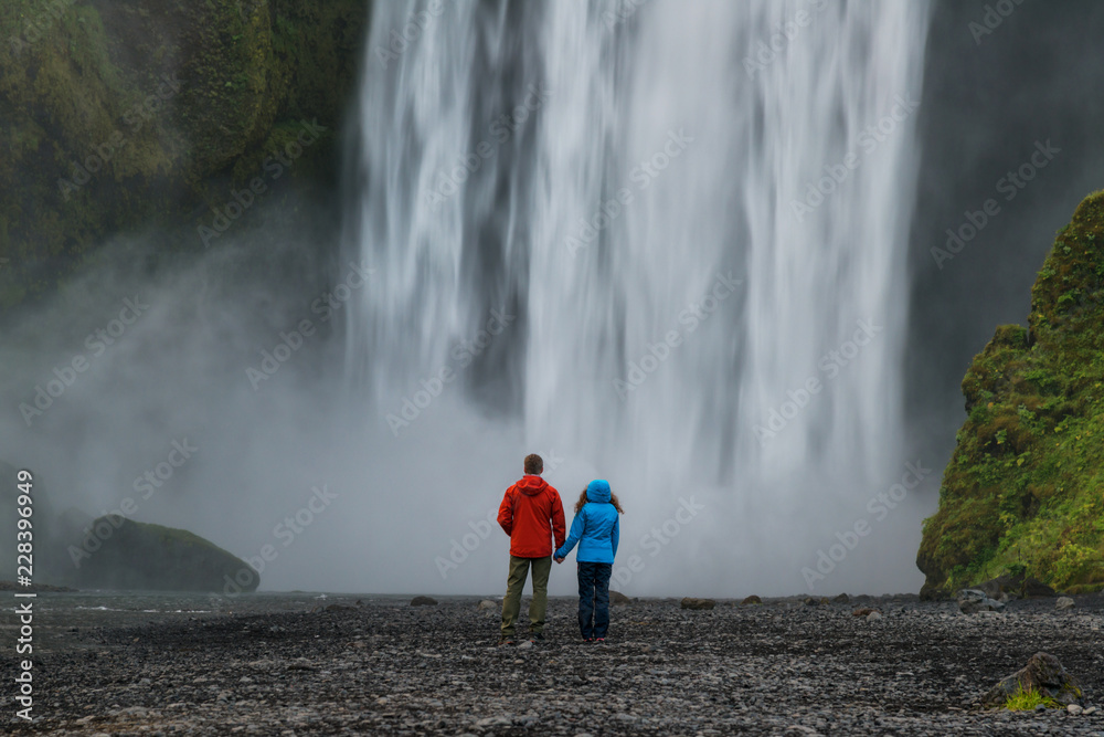 Fototapeta premium Couple looking at powerfull waterfall Skogafoss