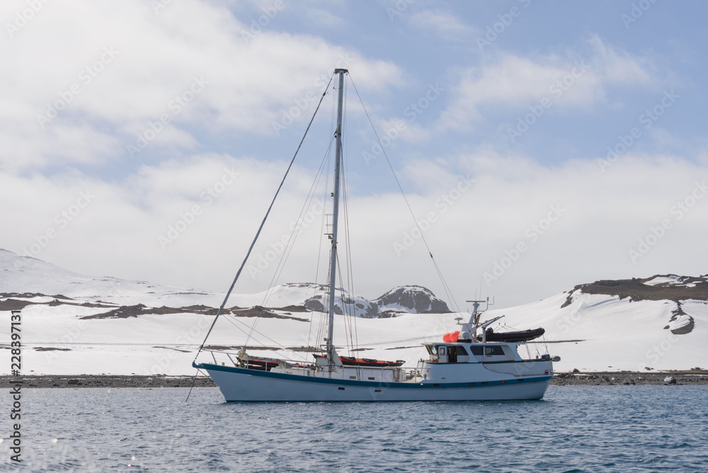 Sailing yacht and iceberg in antarctic sea