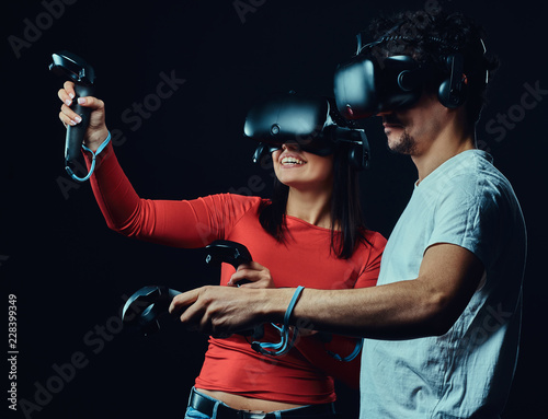 Happy friends playing video games wearing virtual reality glasses with controllers.