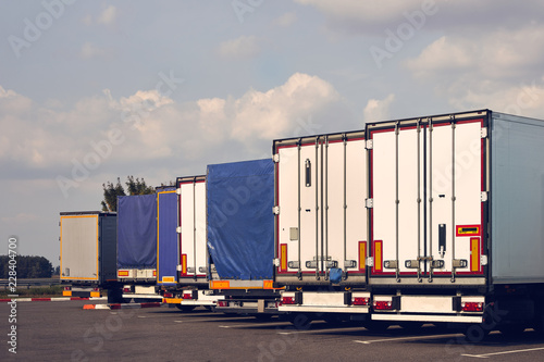 Modern trucks of various models are in a row on truck stop. Back view. © Slava