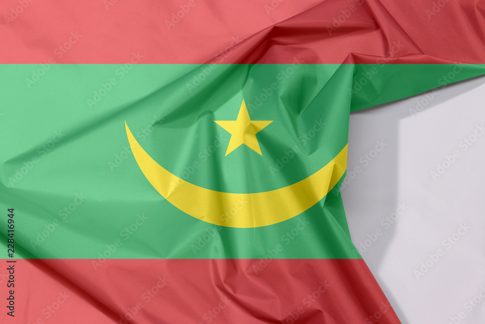 Mauritania fabric flag crepe and crease with white space, Two red stripes flanking a green field with a golden crescent and star. Mauritania fabric flag crepe and crease with white space, Two red stripes flanking a green field with a golden crescent and star.
